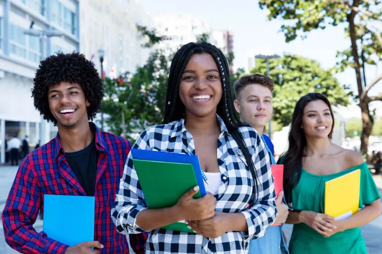 Students smiling while holding folders